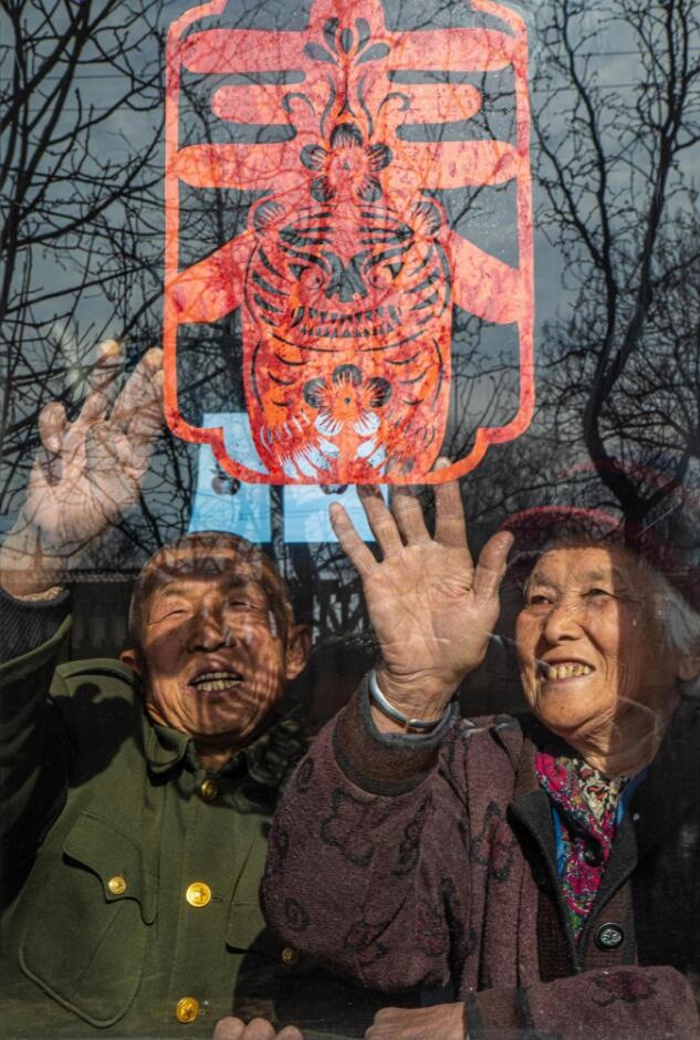 臘月里，霍州市師莊鄉(xiāng)馮南垣村村民師榮光(左)在災(zāi)后重建的新家里貼窗花。(霍州市委宣傳部供圖)