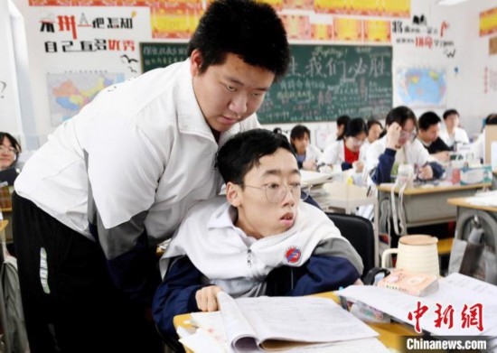 朱金祥(左)把鐘華強放到課堂座位上后，都要把他擺正好，確認(rèn)安全后才回到自己的座位上。 卓忠偉 攝