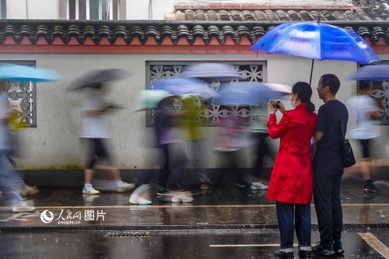6月7日，在浙江省2023年普通高校招生考試鎮(zhèn)海中學(xué)考點(diǎn)，家長冒雨目送子女進(jìn)入考場。人民網(wǎng) 章勇濤攝