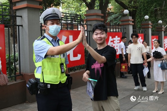6月7日8時許，武漢中學(xué)考點(diǎn)門口，交警在維護(hù)秩序，并?？忌鸢耦}名。人民網(wǎng)記者 肖璐欣攝