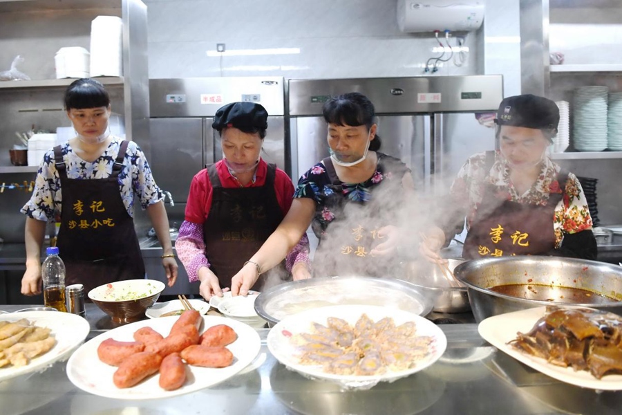 福建三明市沙縣區(qū)一家小吃店工作人員在為客人準備特色小吃。 新華社記者 林善傳 攝