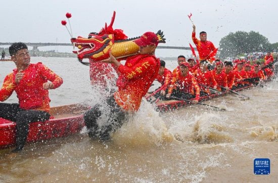 6月22日，在湖南省岳陽市湘陰縣湘江臨資口水域，參加龍舟賽的隊(duì)員接“龍頭”下水。