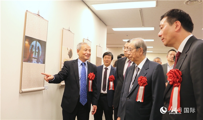 “湖州印象”攝影展主創(chuàng)、世界華人攝影協(xié)會(huì)副會(huì)長(zhǎng)馮學(xué)敏向吳江浩大使、福田康夫前首相等嘉賓介紹展出作品。（人民網(wǎng) 許可攝）