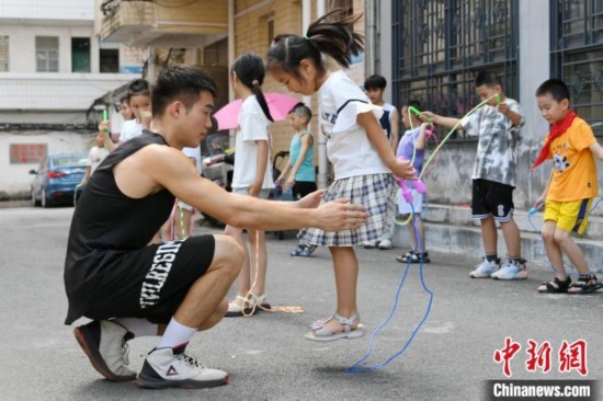 圖為大學(xué)生志愿者在教孩子們學(xué)跳繩。廖光福 攝