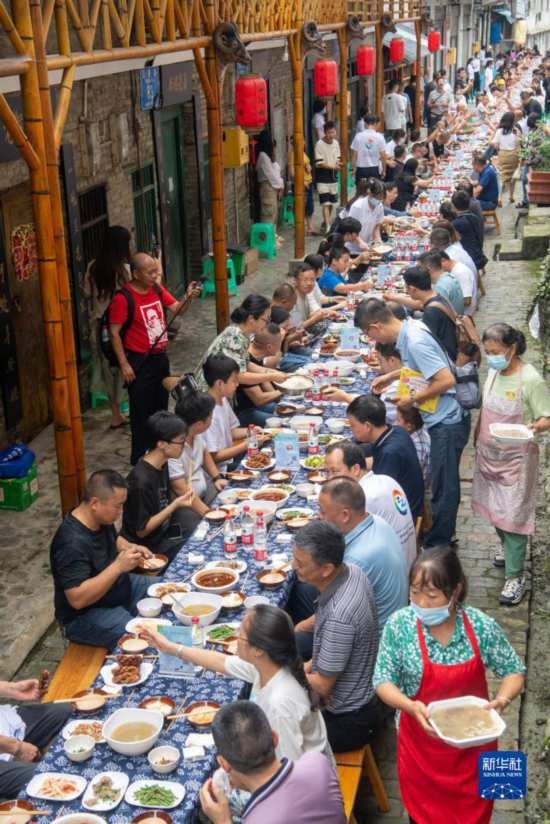 7月29日，在重慶市綦江區(qū)安穩(wěn)鎮(zhèn)，人們在“苗家伏羊節(jié)”上吃長桌宴。新華社記者 唐奕 攝