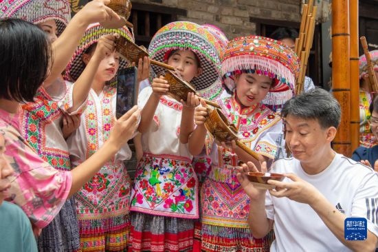 7月29日，在重慶市綦江區(qū)安穩(wěn)鎮(zhèn)，當?shù)鼐用裨凇懊缂曳蚬?jié)”上用傳統(tǒng)習俗向游客表達祝福。新華社記者 唐奕 攝