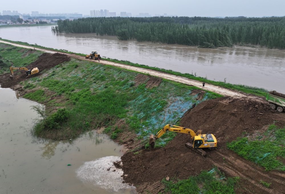 工人操作機(jī)械在白溝河左堤白溝新城高橋村段進(jìn)行除險(xiǎn)加固作業(yè)（8月4日攝，無人機(jī)照片）。新華社記者 朱旭東 攝