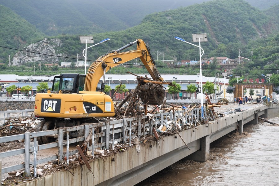 8月1日，在北京市門頭溝區(qū)水峪嘴村村口，一臺(tái)挖掘機(jī)在清理阻斷橋梁交通的雜物。目前該條道路已經(jīng)疏通完成。新華社記者 鞠煥宗 攝