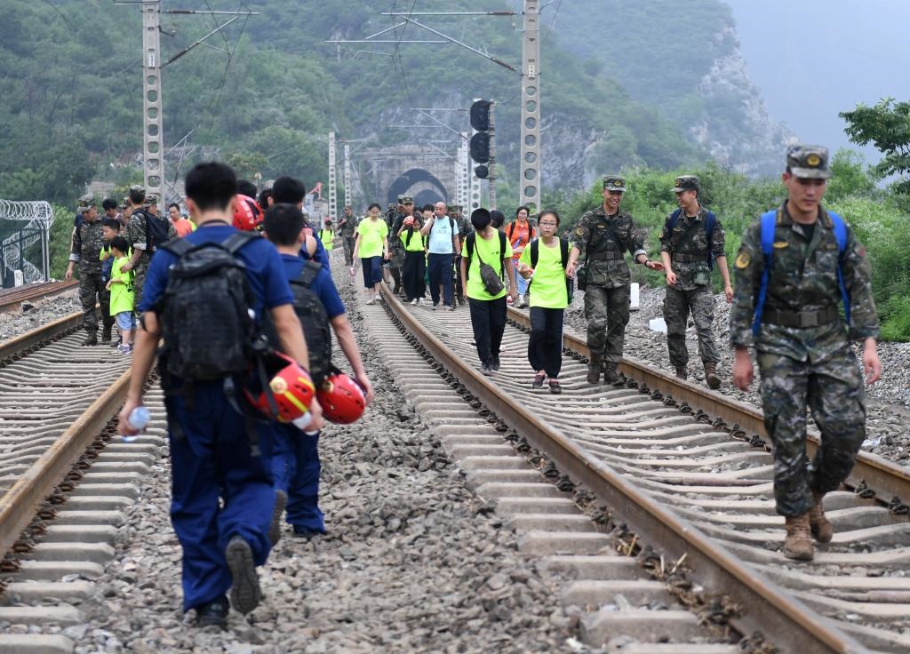 8月2日，部分滯留在北京市門頭溝山區(qū)受困列車的旅客，在救援人員幫助下前往轉(zhuǎn)運客車。新華社記者張晨霖 攝