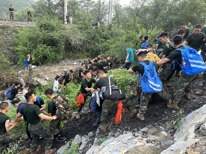 8月2日，Z180次受困列車的旅客在武警北京總隊(duì)機(jī)動(dòng)第三支隊(duì)官兵的幫助下徒步前往轉(zhuǎn)運(yùn)客車（手機(jī)照片）。新華社記者 王艷剛 攝