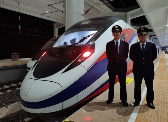 劉銀能（右一）與中國(guó)師父鄔俊鴻在動(dòng)車組前合影。受訪者供圖