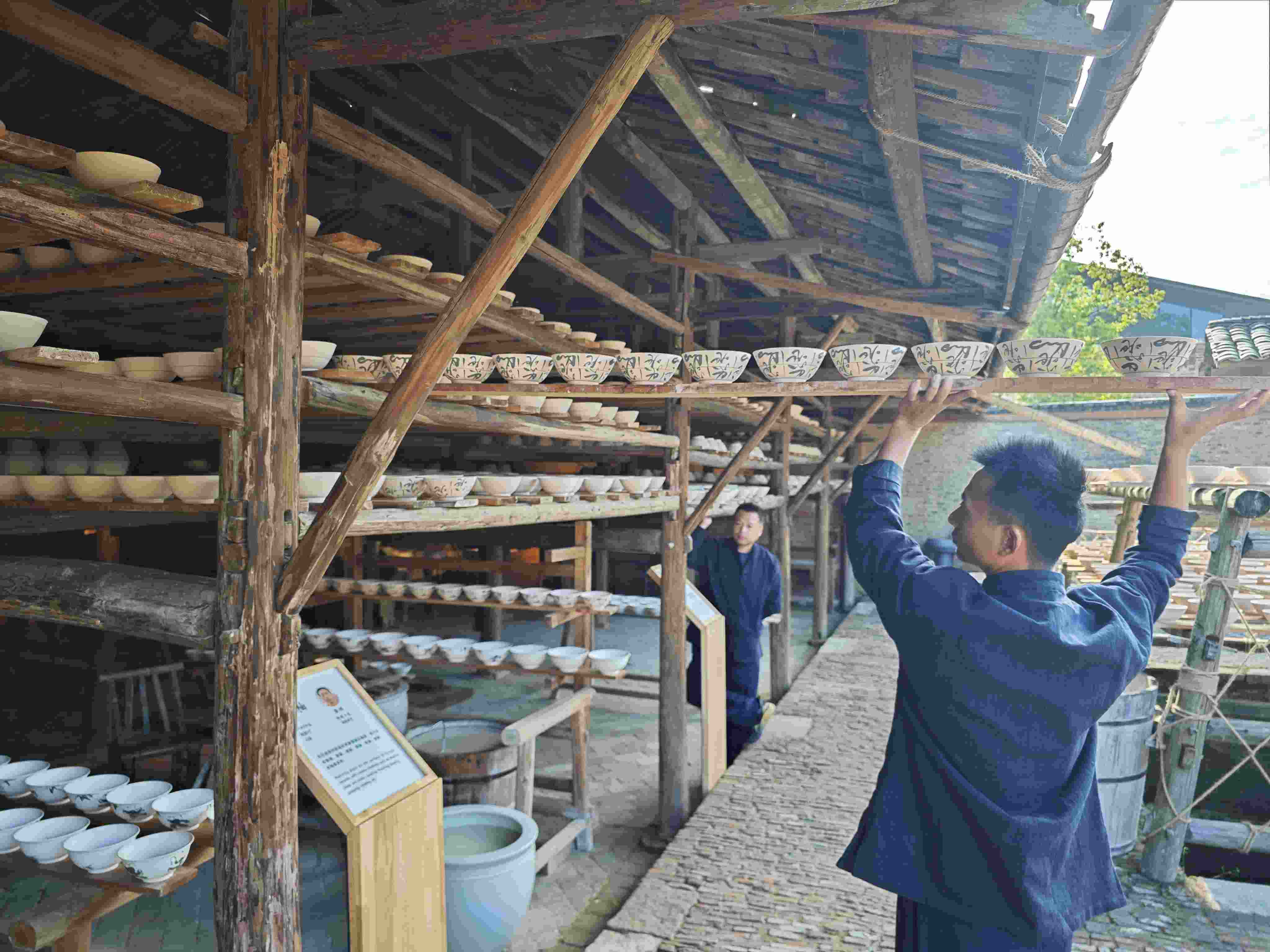 △陶陽里歷史文化街區(qū)里，工匠將陶瓷工藝品放到架上晾干。（總臺(tái)央視記者彭漢明拍攝）