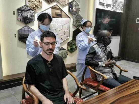 2023“一帶一路”媒體合作論壇聯(lián)合采訪團團員在九牛草展示館體驗艾灸。（本報記者 黃超攝）