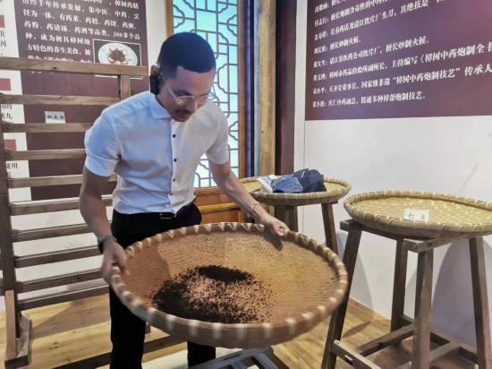 2023“一帶一路”媒體合作論壇聯(lián)合采訪團團員在非遺文化展示館體驗中藥炮制技藝。（本報記者 黃超攝）