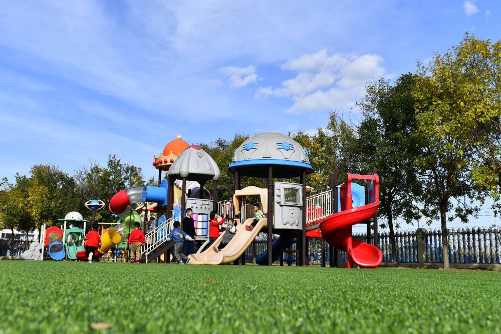 在山東省東營市墾利區(qū)楊廟社區(qū)幼兒園，孩子們在老師的帶領(lǐng)下進行戶外活動（2021年10月19日攝）。新華社記者 郭緒雷 攝