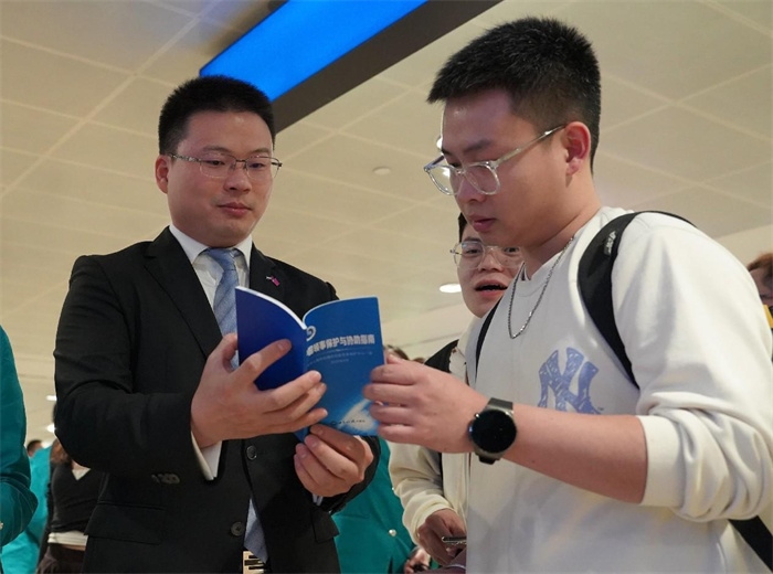 工作人員（左一）在發(fā)放《中國(guó)領(lǐng)事保護(hù)與協(xié)助指南》。 中國(guó)駐迪拜總領(lǐng)事館供圖
