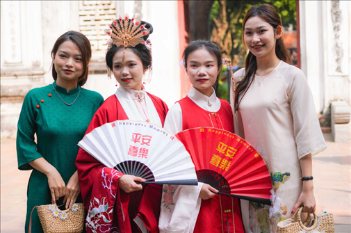 身穿古裝的中國(guó)游客和身穿越南傳統(tǒng)服飾奧黛的越南青年在文廟門(mén)前合影。