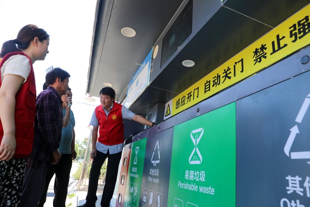 在安徽省合肥市長豐縣莊墓鎮(zhèn)棗林社區(qū)，志愿者指導(dǎo)居民使用智能垃圾分類回收設(shè)備（2023年9月1日攝）。新華社記者 曹力 攝