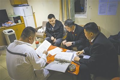 圖②：法官向船長講解相關(guān)法律規(guī)定，查看船舶資料，并與船方辦理扣押船舶的手續(xù)。