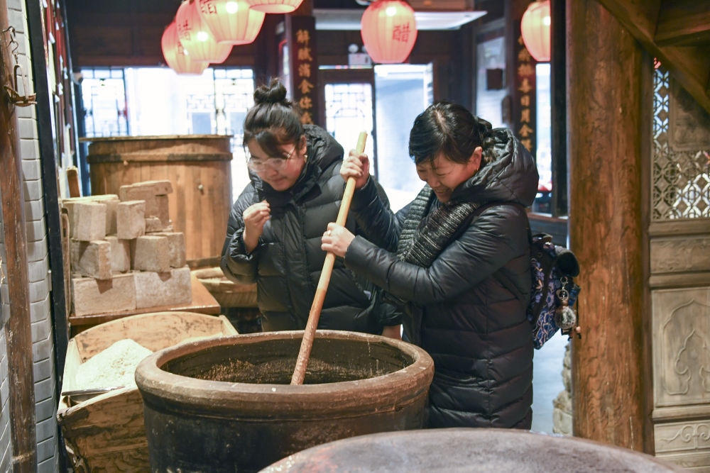 游客在平遙古城東湖老醋坊內(nèi)體驗(yàn)陳醋發(fā)酵打耙（2022年1月28日攝）。新華社發(fā)（梁生仁攝）