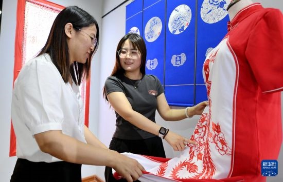 5月31日，在衡水市阜城縣一家剪紙工作室，游客在觀賞帶有剪紙元素的旗袍。