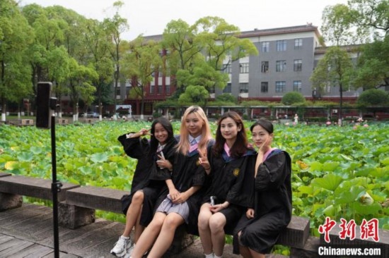 6月19日，時值一年畢業(yè)季，四川大學(xué)望江校區(qū)荷花池里的荷花盛開，成為了畢業(yè)生們的打卡圣地，吸引了眾多畢業(yè)生拍照留念。圖為畢業(yè)生在荷花池邊拍照留念。中新社記者 安源 攝