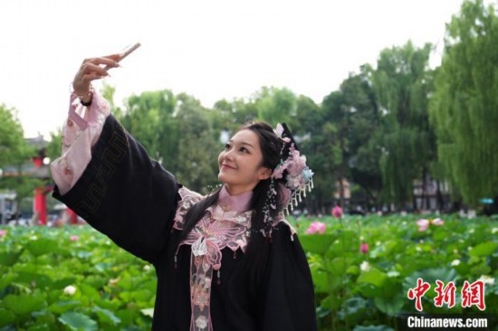 6月19日，時值一年畢業(yè)季，四川大學(xué)望江校區(qū)荷花池里的荷花盛開，成為了畢業(yè)生們的打卡圣地，吸引了眾多畢業(yè)生拍照留念。圖為畢業(yè)生在荷花池邊拍照留念。中新社記者 安源 攝