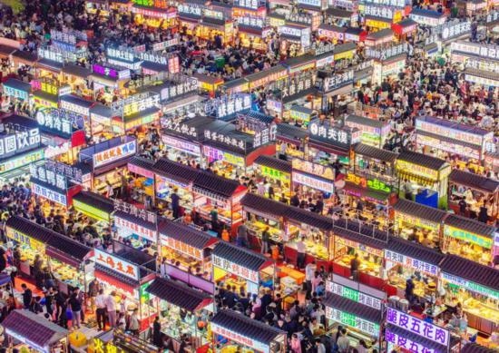 2024年4月21日，人們?cè)诤颖笔≌h小商品夜市品嘗美食（無(wú)人機(jī)照片）。新華社發(fā)（武志偉 攝）