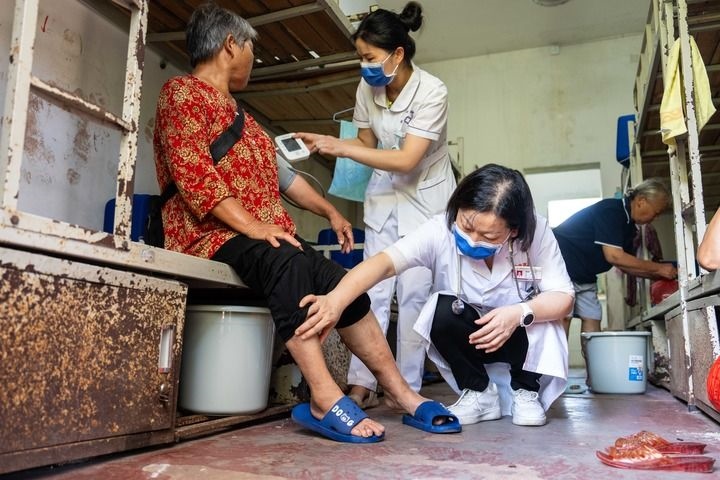 2024年7月30日，在湖南省湘潭縣河口中學(xué)安置點，醫(yī)務(wù)人員為受洪水影響而轉(zhuǎn)移安置的群眾檢查身體。 新華社記者 陳思汗 攝