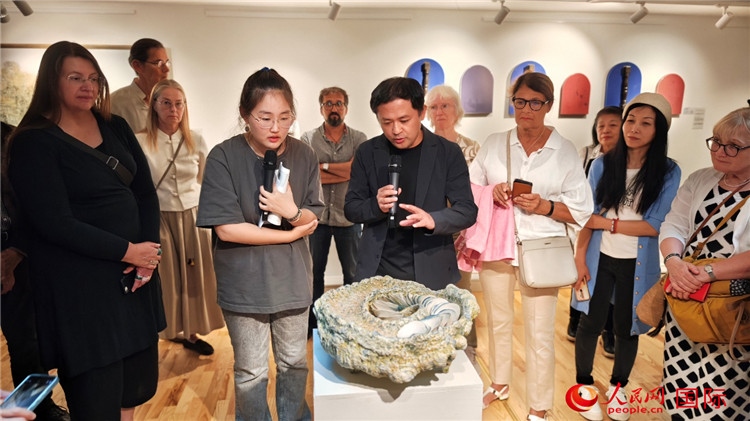 參展人、景德鎮(zhèn)陶瓷大學(xué)設(shè)計(jì)藝術(shù)學(xué)院副院長(zhǎng)余劍峰（中）向來賓介紹參展作品。人民網(wǎng)記者 殷淼攝