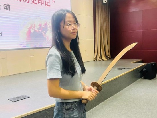 圖為南開大學(xué)社會(huì)實(shí)踐隊(duì)學(xué)生代表呼月紅在學(xué)術(shù)交流活動(dòng)現(xiàn)場，展示河間調(diào)研行中獲贈(zèng)的一戰(zhàn)華工蔡世春曾使用過的一把大刀。林卓瑋 攝