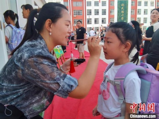 圖為衡水市利民路小學(xué)，老師為學(xué)生點(diǎn)朱砂痣，寓意開啟智慧。張松 攝