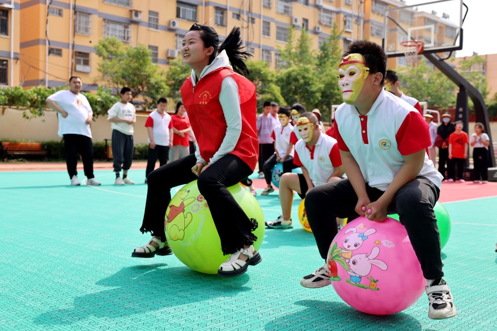 2024年5月17日，在山東省棗莊市市中區(qū)特殊教育中心，青年志愿者與智力障礙學(xué)生一起做游戲。新華社發(fā)（孫中喆攝）