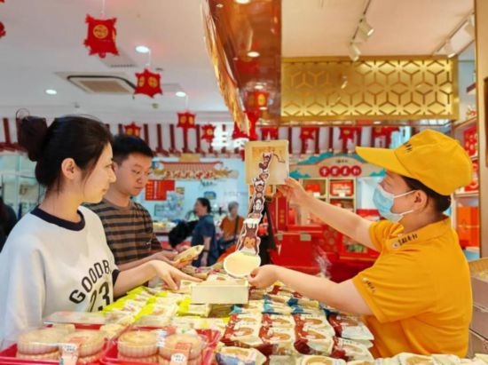 北京稻香村一家門店內(nèi)，售貨員向顧客展示新上市的月餅禮盒。（受訪者供圖）