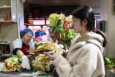游客挑選好麻辣燙菜品后排隊等待加工。新華社記者 范培珅 攝
