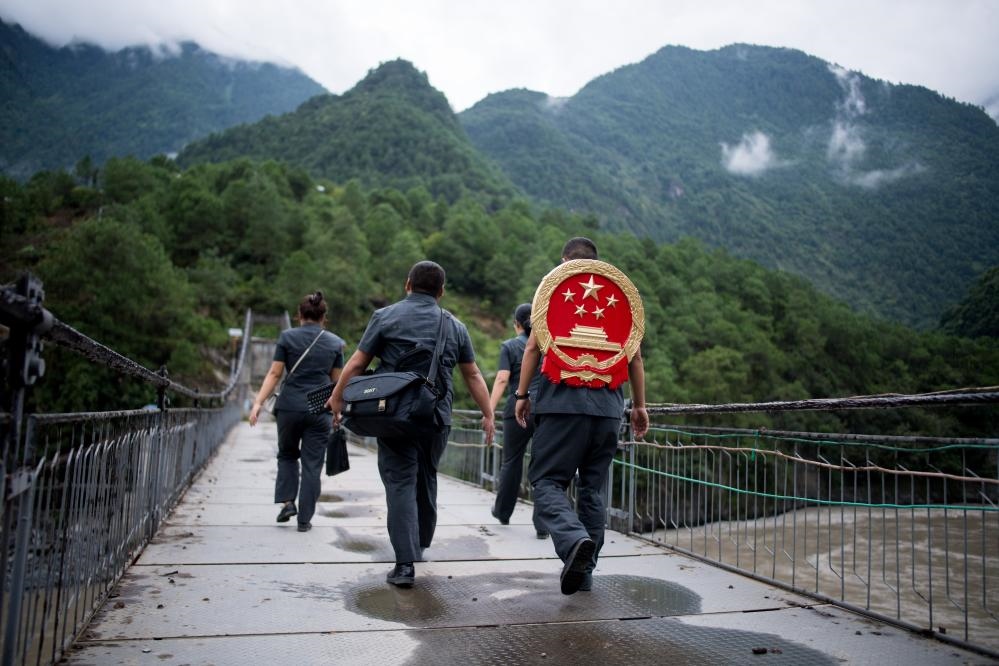 云南省怒江傈僳族自治州貢山縣人民法院法官鄧興背著國徽與同事們跨過怒江（2019年8月30日攝）。怒江高山峽谷眾多，交通不便，為方便群眾、更好地開展法律服務(wù)，背著國徽攀高山、過索橋、躲落石、鉆老林……成為鄧興法官的工作常態(tài)。新華社記者 江文耀 攝