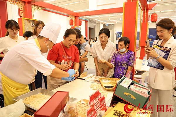 演出前，在天津桂發(fā)祥十八街麻花制作技藝非遺體驗展臺前，泰國民眾體驗天津麻花制作。人民網(wǎng)記者 楊一攝