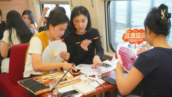 10月1日，旅客們在G1634次列車上給油紙傘作畫。新華社記者周義 攝