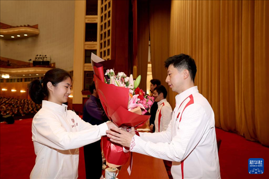11月15日，一名學(xué)生代表在報(bào)告會(huì)上向乒乓球運(yùn)動(dòng)員馬龍（右）獻(xiàn)花。新華社記者 李明 攝
