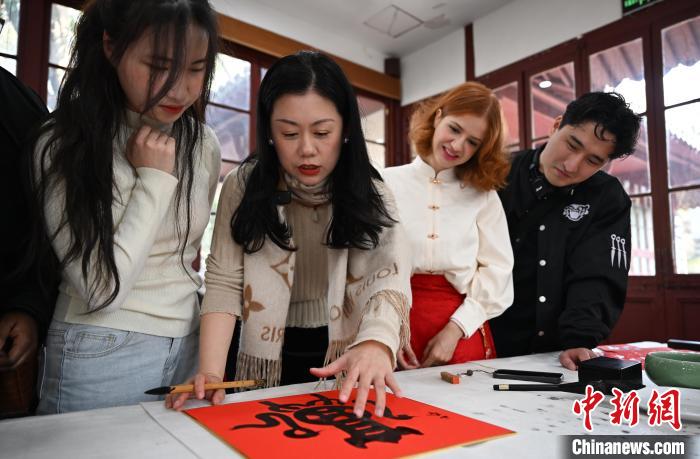 1月20日，西泠印社社員李硯（左二）為外籍留學(xué)生講述蛇年福字貼創(chuàng)作靈感。當(dāng)日，來自巴西、馬來西亞、加納、哈薩克斯坦的外籍留學(xué)生在浙江杭州西泠印社體驗(yàn)福貼、春聯(lián)和篆刻，感受古老的中國傳統(tǒng)文化。中新社記者 王剛 攝