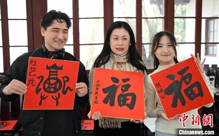 1月20日，外籍留學(xué)生和西泠印社社員李硯(中)展示各自創(chuàng)作的福貼。當(dāng)日，來自巴西、馬來西亞、加納、哈薩克斯坦的外籍留學(xué)生在浙江杭州西泠印社體驗(yàn)福貼、春聯(lián)和篆刻，感受古老的中國傳統(tǒng)文化。中新社記者 王剛 攝