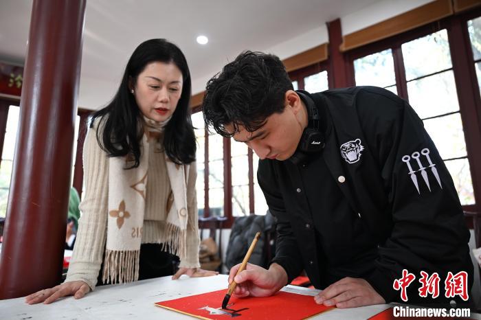 1月20日，外籍留學(xué)生在西泠印社社員李硯指導(dǎo)下寫福。當(dāng)日，來自巴西、馬來西亞、加納、哈薩克斯坦的外籍留學(xué)生在浙江杭州西泠印社體驗(yàn)福貼、春聯(lián)和篆刻，感受古老的中國傳統(tǒng)文化。中新社記者 王剛 攝