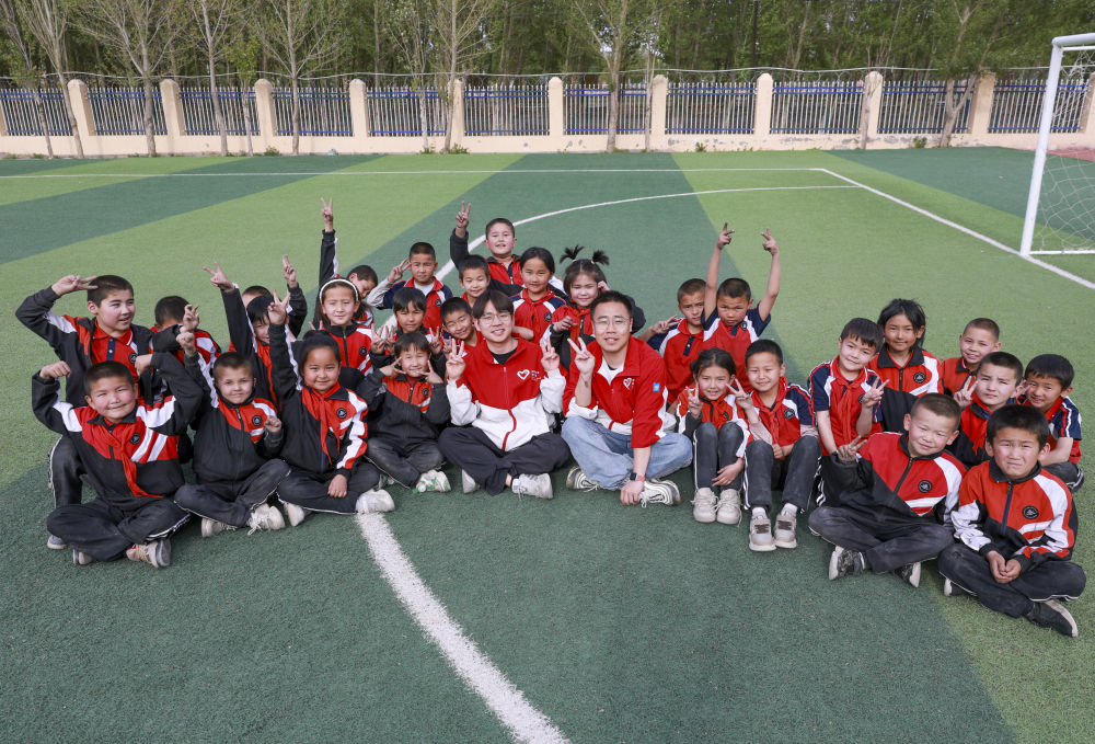 4月23日，在新疆克州阿圖什市哈拉峻鄉(xiāng)謝依特小學(xué)，支教教師王俊文（中左）、李軻凡（中右）和學(xué)生在一起。